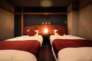 two beds in a room with a light between them at Bettei Koyoi (Adult Only) in Hakone
