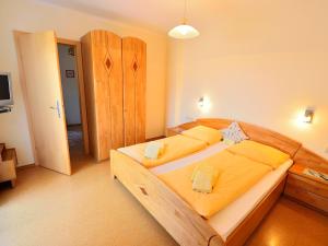 ein Schlafzimmer mit einem großen Holzbett mit gelber Bettwäsche in der Unterkunft Erlebnisbauernhof Urak in Sankt Kanzian am Klopeiner See