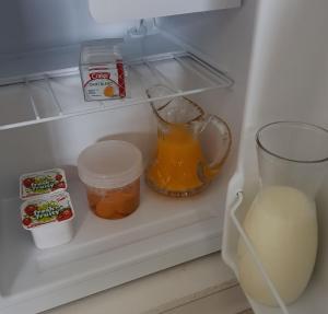 um frigorífico com um jarro de sumo de laranja e um copo de leite em Botanical Haven BnB em Tauranga