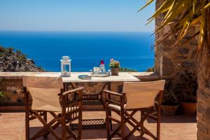 un tavolo e sedie su un balcone con vista sull'oceano di Dorovinis Country Houses ad Anatolí