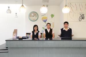 un grupo de tres personas parados detrás de un mostrador en Dung Shin Hotel, en Taitung