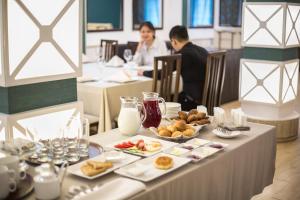 a table with plates of food and people sitting at tables at Mirage Hotel in Qyzylorda