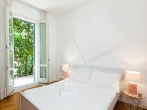 een witte slaapkamer met een bed en een groot raam bij easyhomes - Piola Bazzini in Milaan