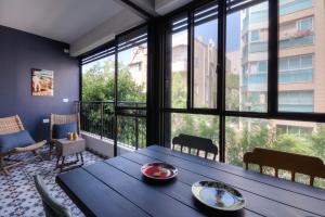 uma sala de jantar com uma mesa e janelas grandes em Yohanan HaSandlar em Tel Aviv