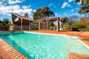 een zwembad met een prieel en een huis bij Breeze Holiday Parks - Grampians in Halls Gap