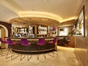 a bar with purple chairs in a restaurant at Hotel Gundolf in Sankt Leonhard im Pitztal