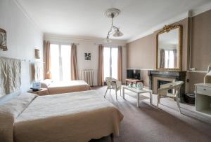 a hotel room with two beds and a fireplace at Hôtel Central in Pau