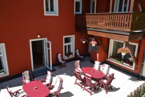 a patio with red tables and chairs and a balcony at Hotel zum Heiligen Geist in Mariazell