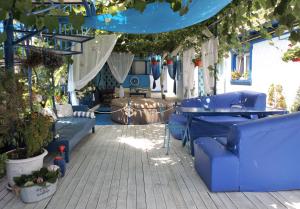 un patio con sillas azules, mesas y plantas en Casa Babica Guesthouse, en Costinesti