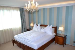 ein Schlafzimmer mit einem großen weißen Bett und einem Kronleuchter in der Unterkunft Hotel zum Heiligen Geist in Mariazell