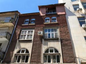 ソフィアにあるBudapest Central Cozy Studio w Working Space and WiFiのレンガ造りの建物で、窓とバルコニーが付いています。