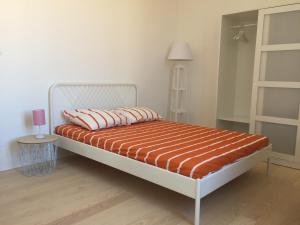 a bed with an orange and white bedspread in a room at Le cœur d'Orques in Saint-Georges-dʼOrques