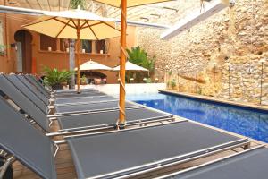 a row of chairs with umbrellas next to a swimming pool at Hotel Gran Claustre Restaurant & Spa in Altafulla