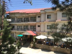 a hotel with tables and umbrellas in front of it at Health Habitat Hotel & Slimming Resort in Pedoulas