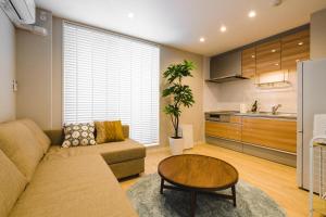 ein Wohnzimmer mit einem Sofa und einem Tisch in der Unterkunft Trip Base HAKATAEKIMAE in Fukuoka
