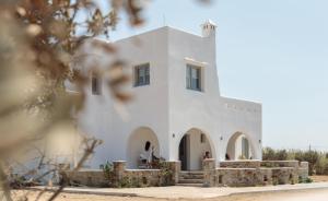 a white building with people sitting in the doorway at Villas vaya in Naxos Chora