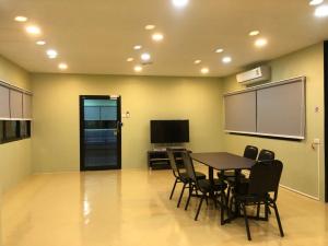 a conference room with a table and chairs and a screen at Thyme Xeriscape Hostel in Kanchanaburi City