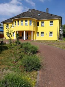 ein gelbes Haus mit einer Straße davor in der Unterkunft Felixanum Hotel & Galerie in Isernhagen