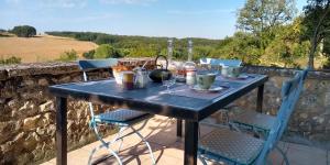 una mesa con comida y bebida en un balcón con una pared de piedra en Montenaut, en Angles-sur-lʼAnglin