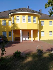 uma casa amarela com um carro estacionado em frente em Felixanum Hotel & Galerie em Isernhagen