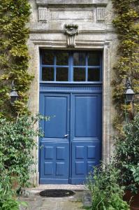 バイユーにあるB&B Jardin et Hotel Particulierの窓付きの石造りの建物の青い扉