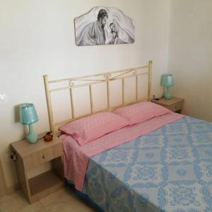 1 dormitorio con 1 cama con sábanas rosas y 2 lámparas en Casa del sole en Portopalo