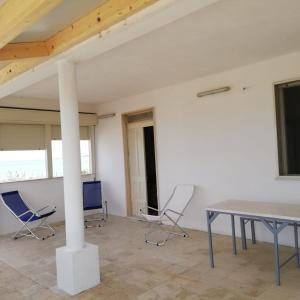 una habitación con sillas, una mesa y un poste en Casa del sole en Portopalo