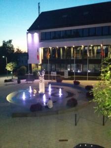 une fontaine devant un bâtiment la nuit dans l'établissement Haus Marquet, à Saint-Vith