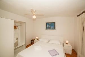 a white bedroom with a bed and a ceiling fan at Apartments Fedrigo in Sutivan