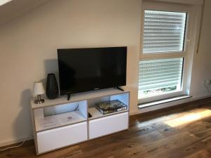 a flat screen tv on a white entertainment center with two windows at Ferienwohnung *stadtnah* ruhig* modern in Ravensburg