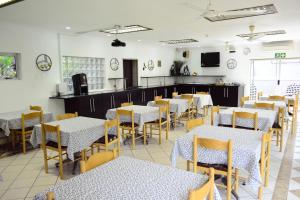 un comedor con mesas blancas y sillas amarillas en Laletsa Lodge, en Durban