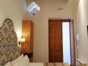 a bedroom with a bed and a chandelier and a door at Santiago 15 Casa Palacio in Seville