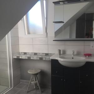 een witte badkamer met een wastafel en een kruk bij Instant d'Evasion in Bar-sur-Aube