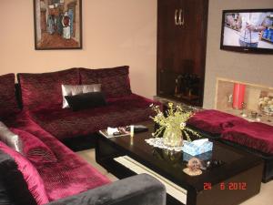 a living room with a red couch and a table at Résidence Dreamland in Sidi Rahal