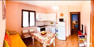 una cocina con mesa y una pequeña cocina con electrodomésticos blancos. en appartamento vacanze Sardegna, en Siniscola