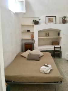 un letto in una camera con pareti bianche e scaffali di La Corte delle Arti a Matino
