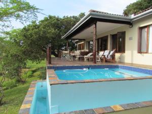 a swimming pool in front of a house at Nkumbe Bush Retreat Family Home in Ponta Malongane