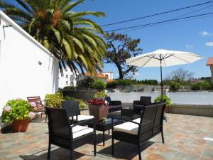 een patio met een tafel en stoelen en een parasol bij Hotel Arboleda in A Lanzada