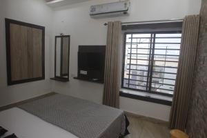 - une chambre avec un lit et une fenêtre avec une télévision dans l'établissement Alakhnanda Guest House, à Varanasi