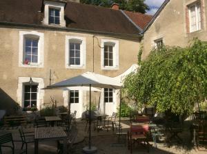 un patio avec des tables et des chaises en face d'un bâtiment dans l'établissement La Basse Cour, à Tanlay