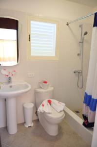 a white bathroom with a toilet and a sink at Hotel Las Palmeras in Sosúa