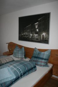 Apartment Rose في تودموس: سرير مع وسائد زرقاء وصورة على الحائط