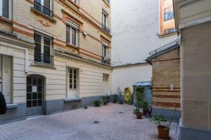 um pátio entre dois edifícios com vasos de plantas em Le Logis de Montmartre em Paris