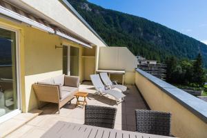 a balcony with chairs and tables on a building at Haus Cristal in Leukerbad