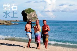 3 Personen stehen am Strand in der Nähe des Ozeans in der Unterkunft Rock House in Eluan