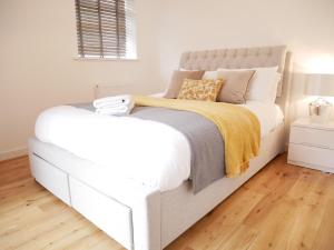 a white bed in a white bedroom with wooden floors at The Gill Gardens Barn - Private Hot Tub Ulverston - Lake District in Ulverston