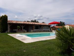 ein Haus mit einem Pool und einem roten Regenschirm in der Unterkunft La Girafe Bleue in Lunas