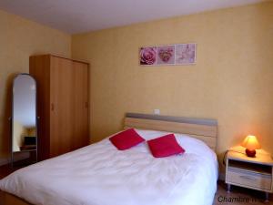 1 dormitorio con 1 cama con 2 almohadas rojas en Auberge Des Petits, en Saint-Igny-de-Vers