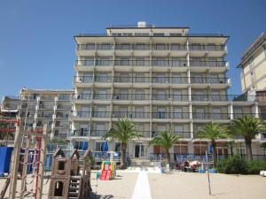 un grande edificio sulla spiaggia con palme di Tourist Residence a San Benedetto del Tronto