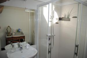 La salle de bains blanche est pourvue d'une douche et d'un lavabo. dans l'établissement La Promenade en Champagne, à Mussy-sur-Seine